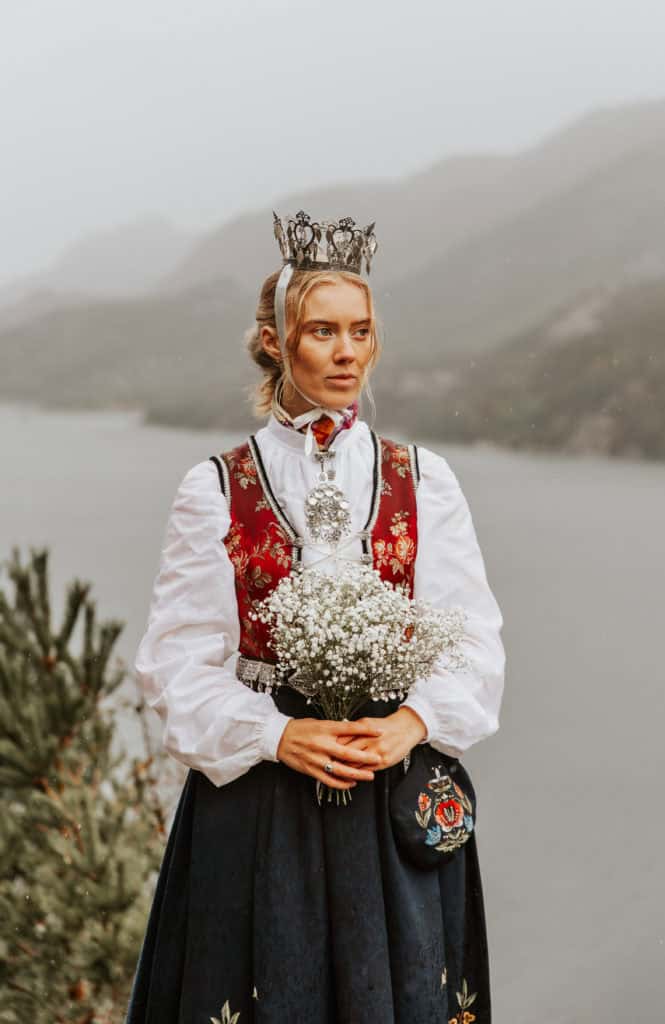 Kvinne i tradisjonell norsk bunad med krone, ved Lysefjorden.
