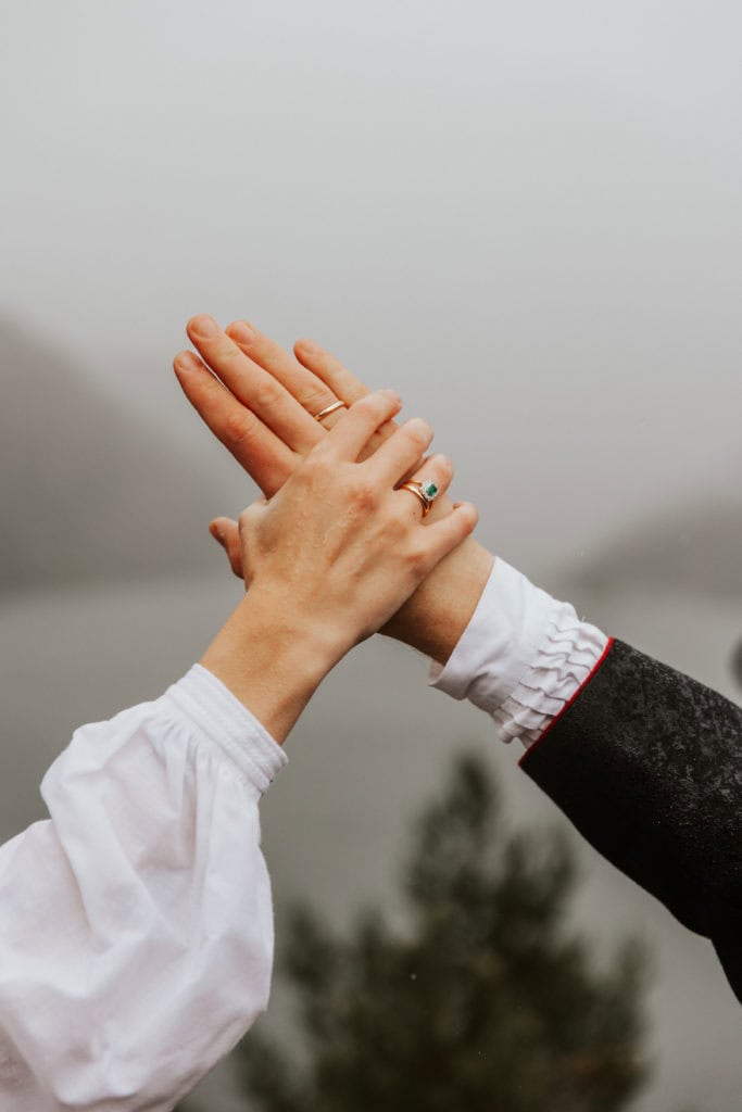 Bryllupsportrett av brudepar som holder hender med fjorden i bakgrunnen.