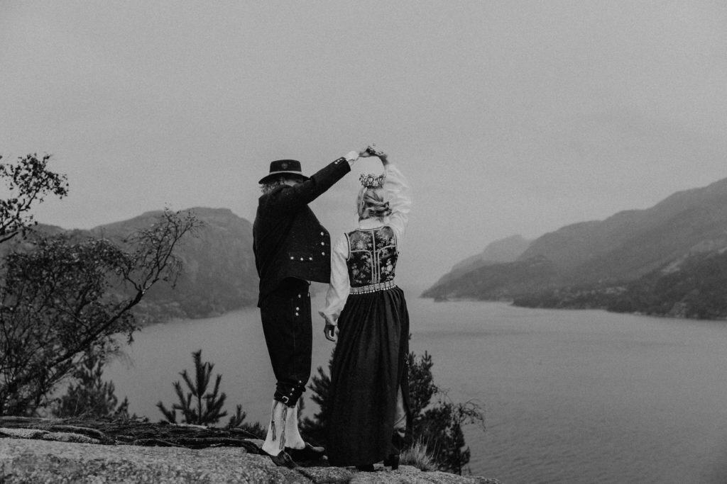 Bryllupsportrett av et par i tradisjonelle klær med Lysefjorden i bakgrunnen.