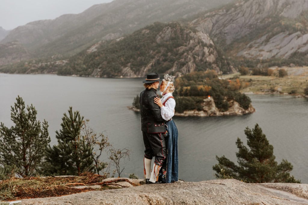 Bryllupsportrett av et par med fjell og vann i bakgrunnen, tatt under en vakker dag ved Lysefjorden.