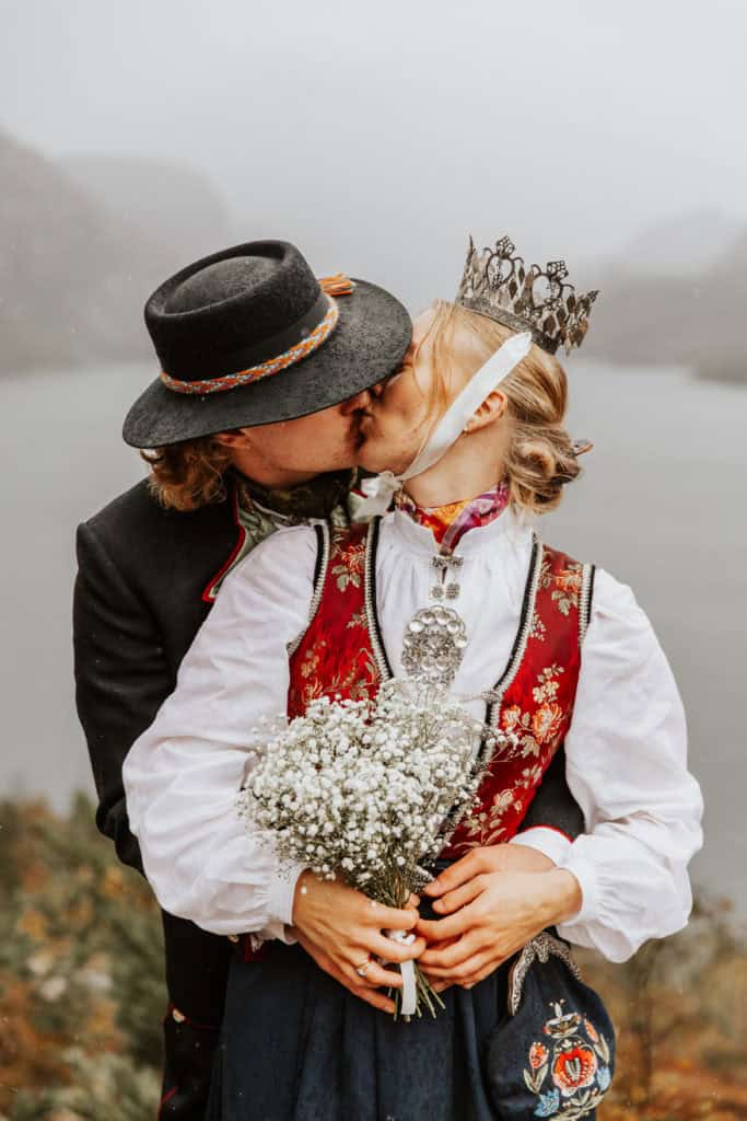 Kjærlighetsbilde av et par i tradisjonelle klær med fjorden i bakgrunnen.